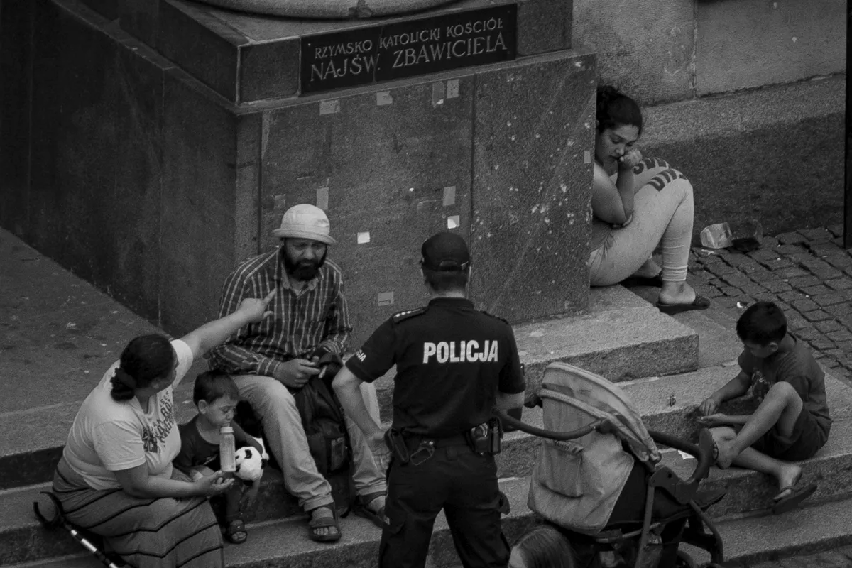 Police officer speaking with a family seated on church steps beside a stroller